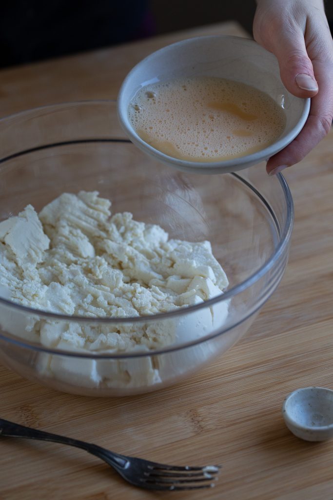 Whisked egg being added to ricotta mix.