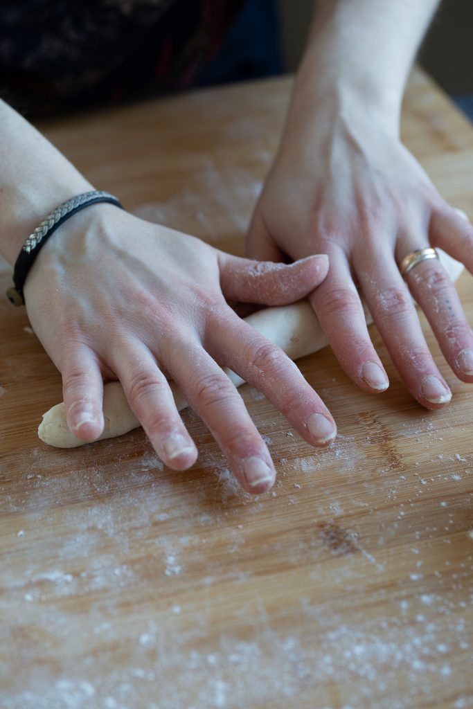 Hands forming dough sausage.