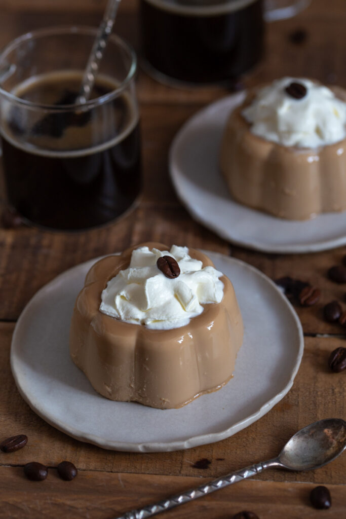 Instant coffee panna cotta served with whipped cream and a coffee bean on top.
