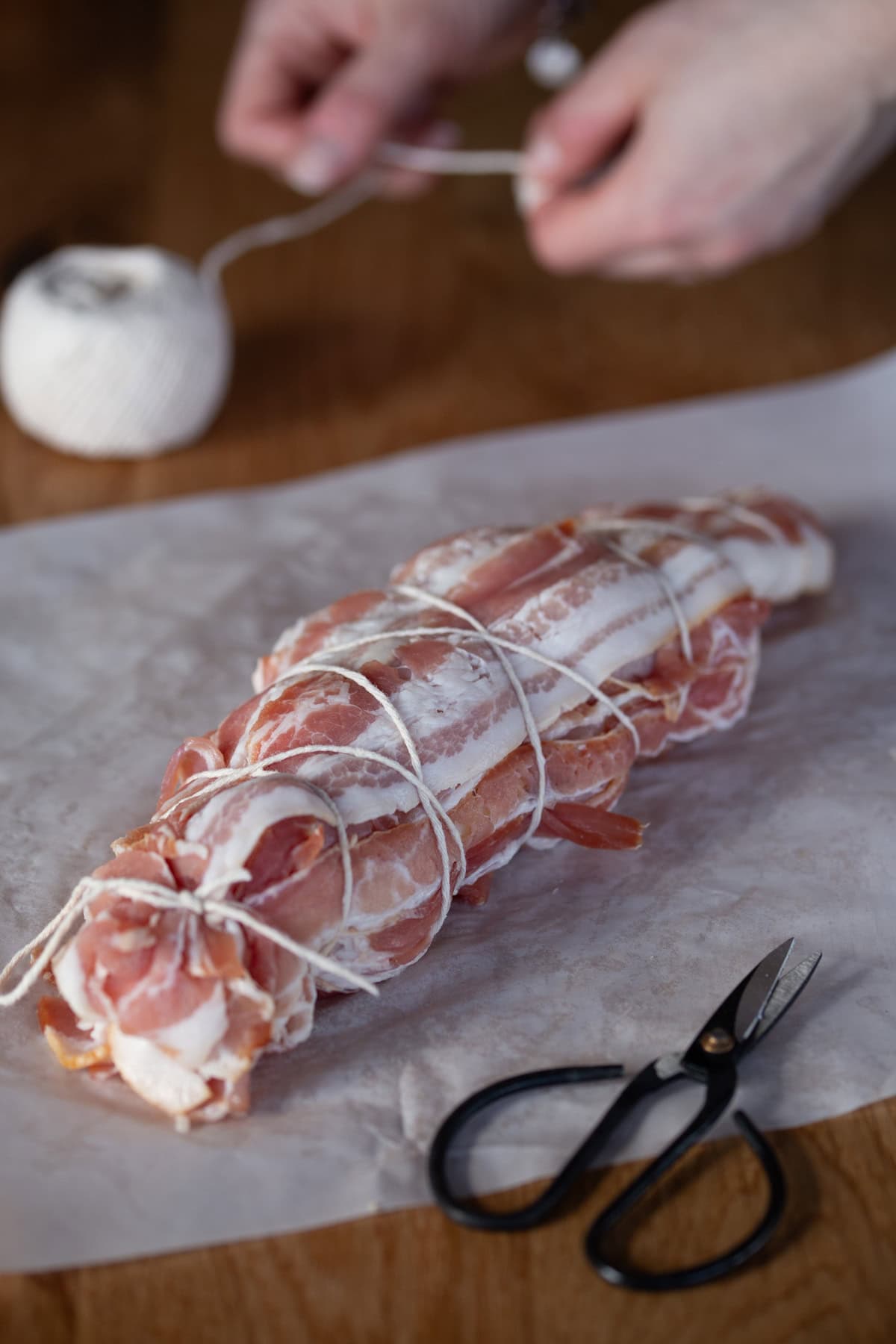 Twine looped around turkey roast wrapped in bacon.