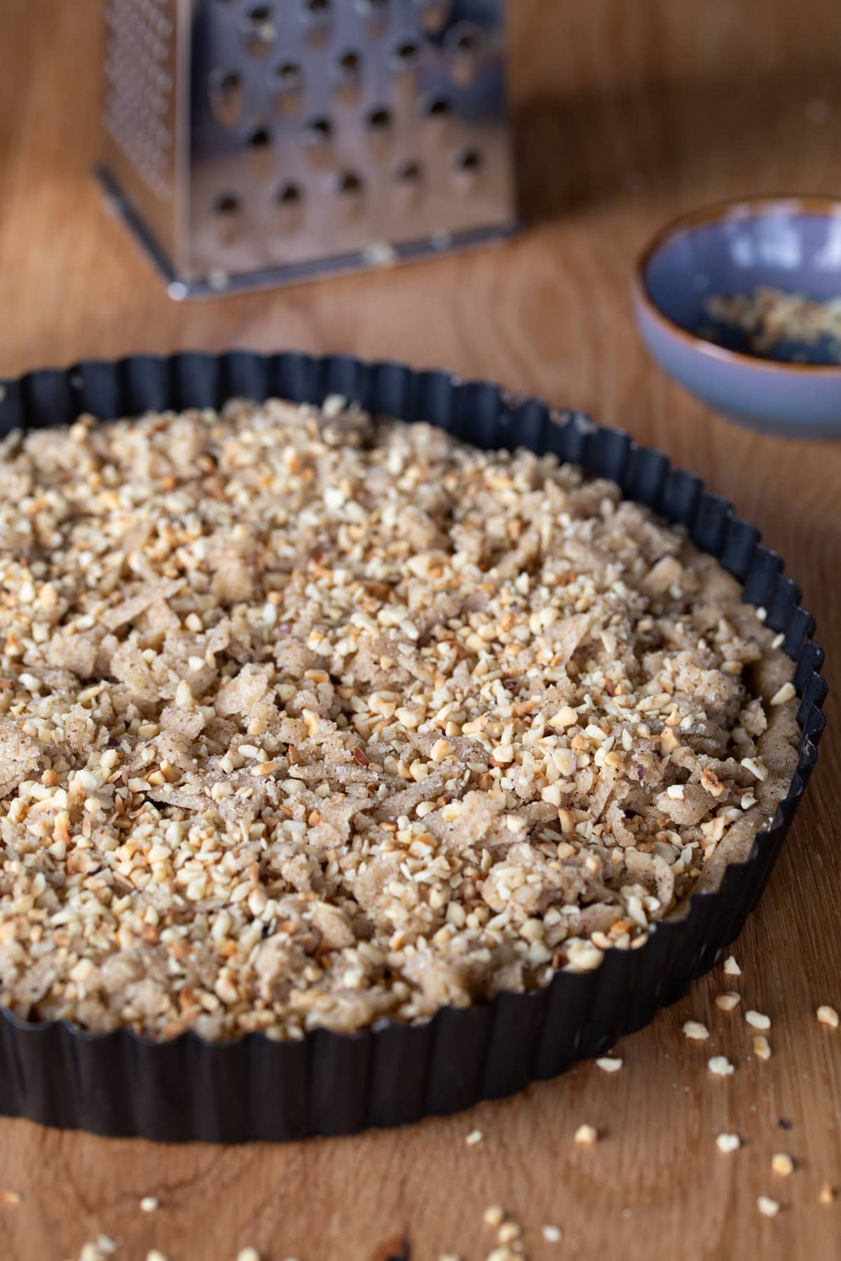 Tart is topped with crumbles and chopped hazelnuts.